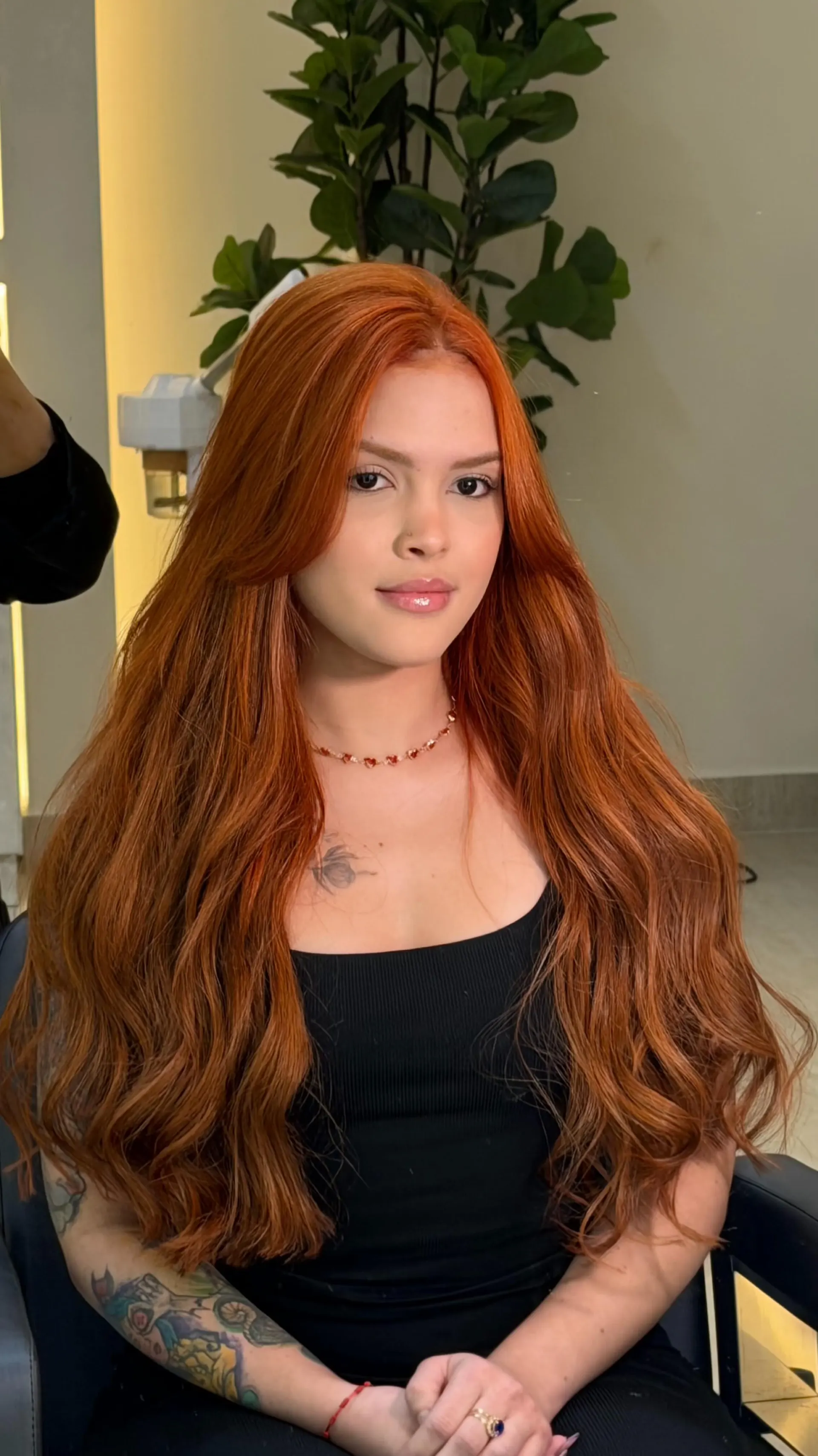Cliente com cabelo ruivo acobreado longo e ondulado, sentada no salão.
