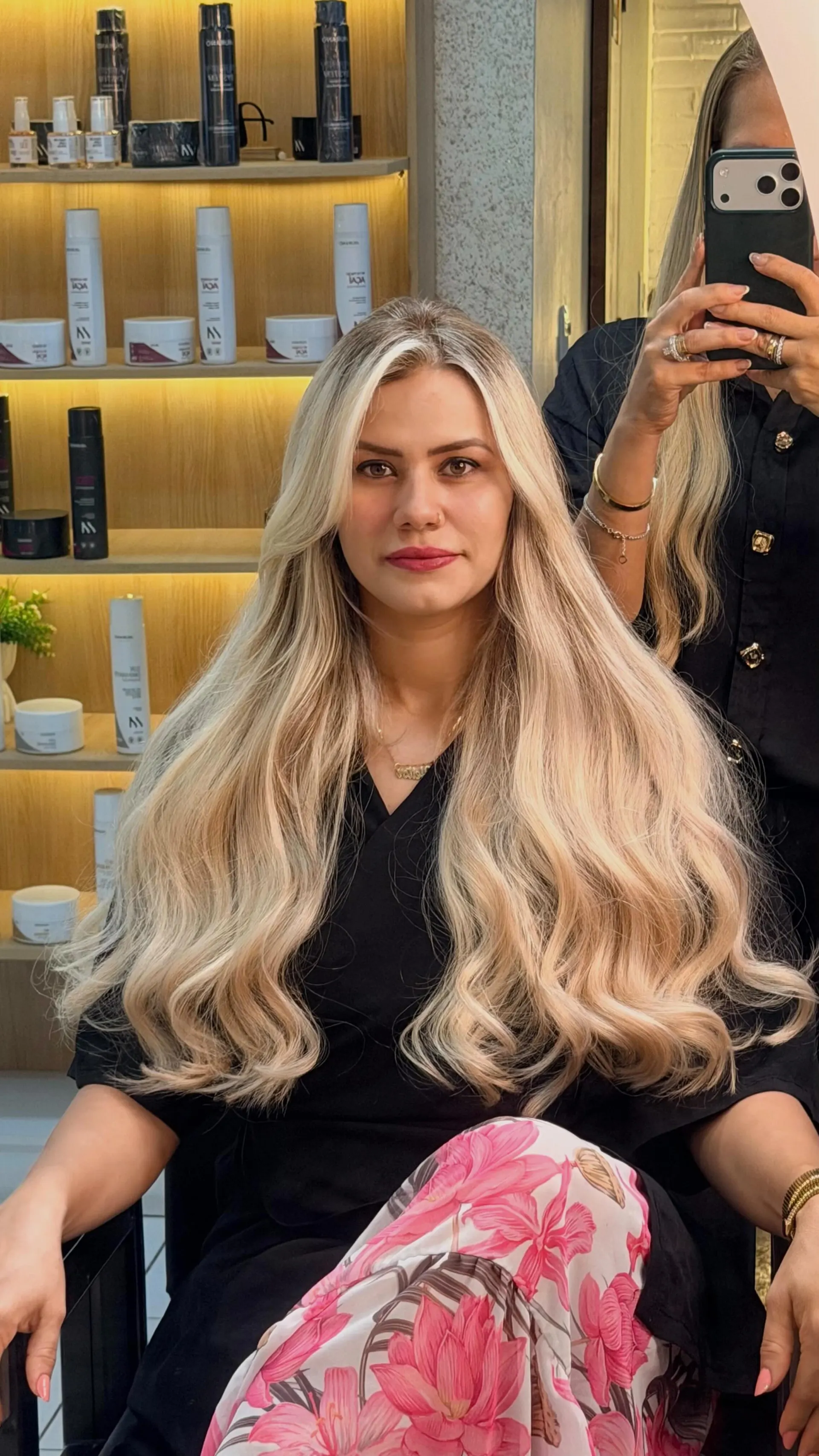 Cliente com cabelo loiro volumoso e ondas abertas, sentada no salão.
