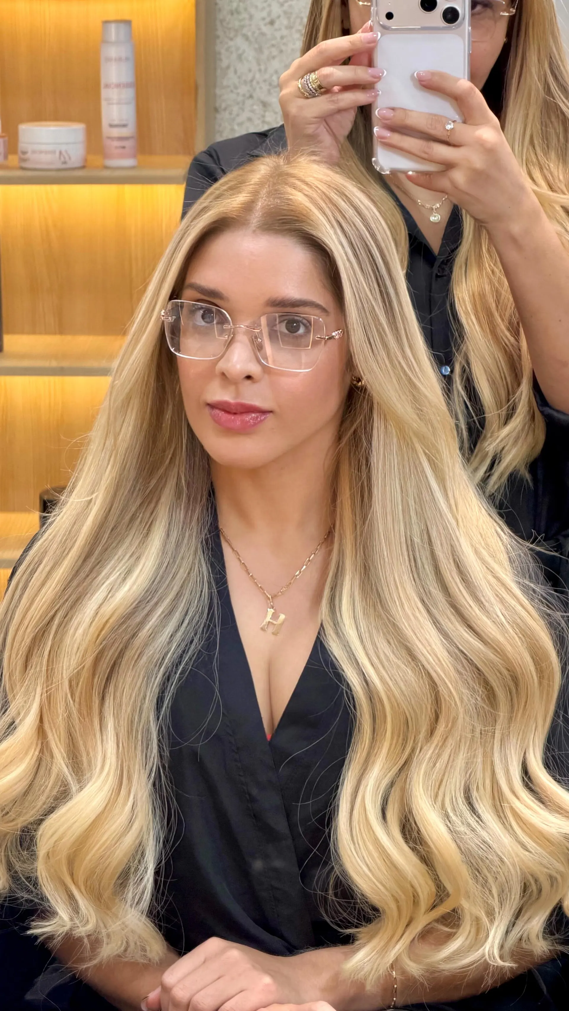 Cliente de óculos com cabelo loiro longo e ondulado.