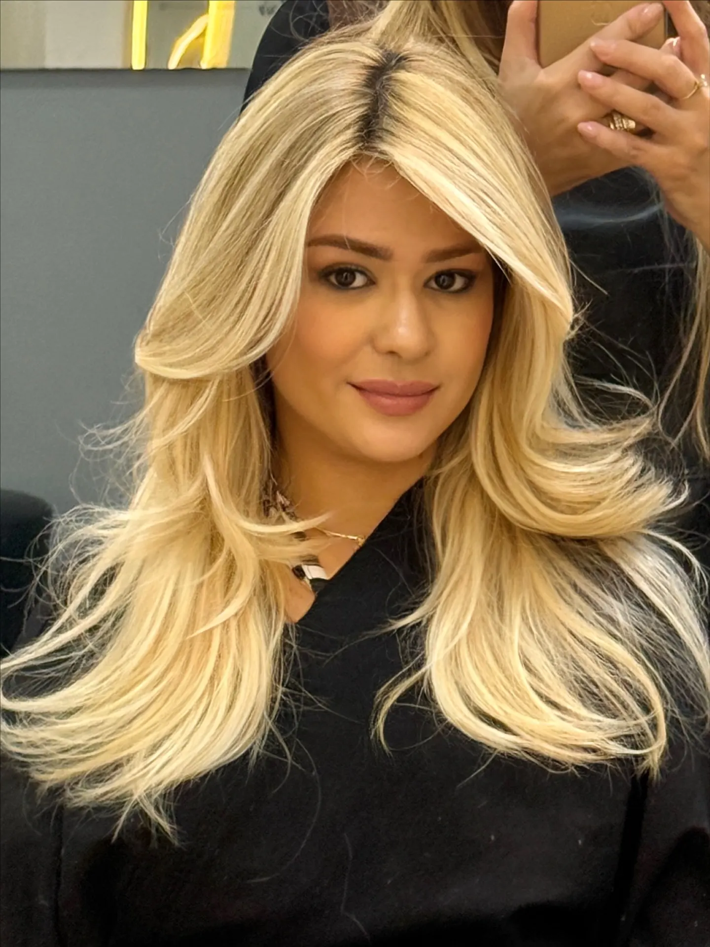 Cliente com cabelo loiro amanteigado, raiz esfumada e mechas no rosto.